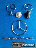 Collection of Mercedes mascots and badges, including a chassis plate