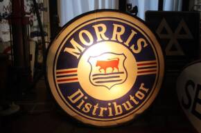 Morris Distributor, a c1930s dealers hanging double sided illuminated sign of tin construction with wooden beading retaining the clear glass illustrated out panels. Both white interior panels cracked. A rare survivor in working order.