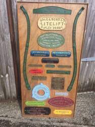 Metal name plates on a display board - The Oxford Steam Plough, Blackston, R A Lister & Co, Land Rover, Ransomes, Howard, Ruston & Hornsby, Ogle & Sons, M A Bate Launceston, Bentalls, W. Woodbridge, Bath and many more