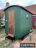 Shepherds Hut of modern construction, built on an oak chassis and standing on steel wheels, a fully insulated build with marine ply barrel roof, fitted out for power with fuse box and outside connection.